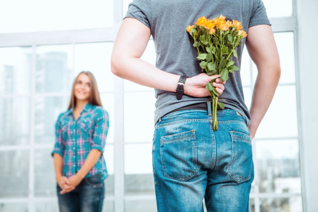 A man surprises a woman with flowers.
